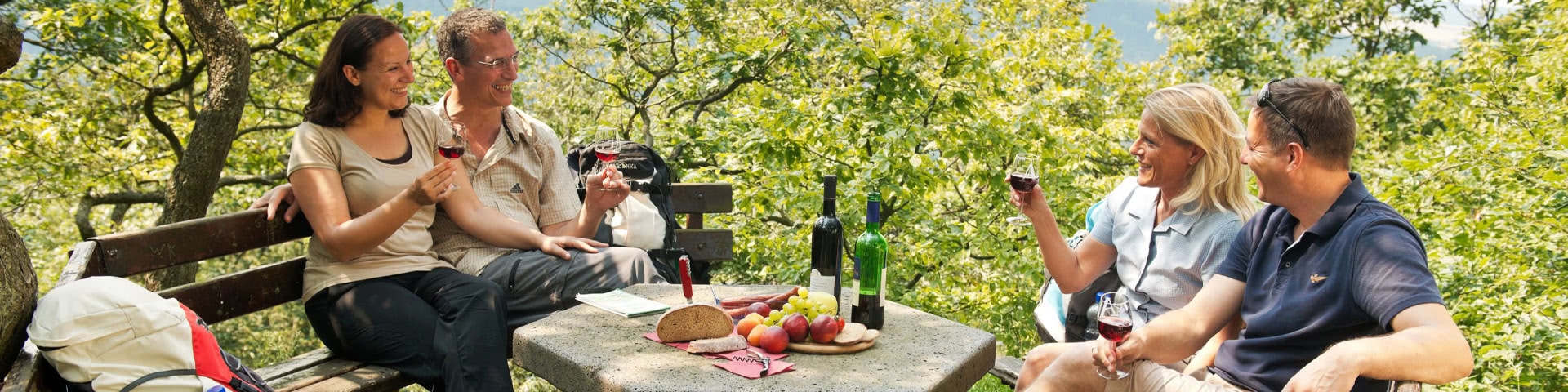 Zwei Pärchen sitzen an einem Picknick-Platz und trinken Wein im Ahrtal