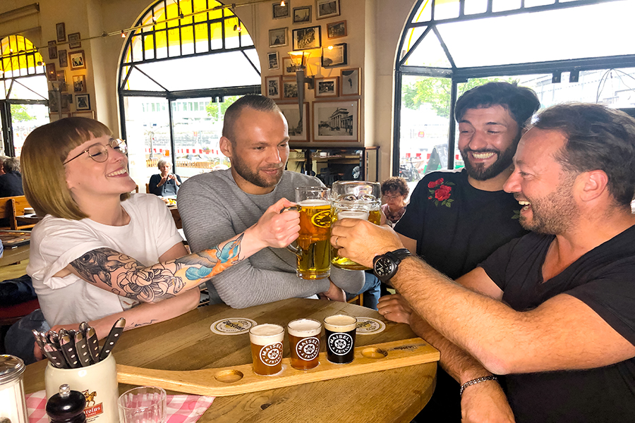 Eine Gruppe sitzt an der der Theke im Restaurant Berliner Republik und stößt mit Bier an