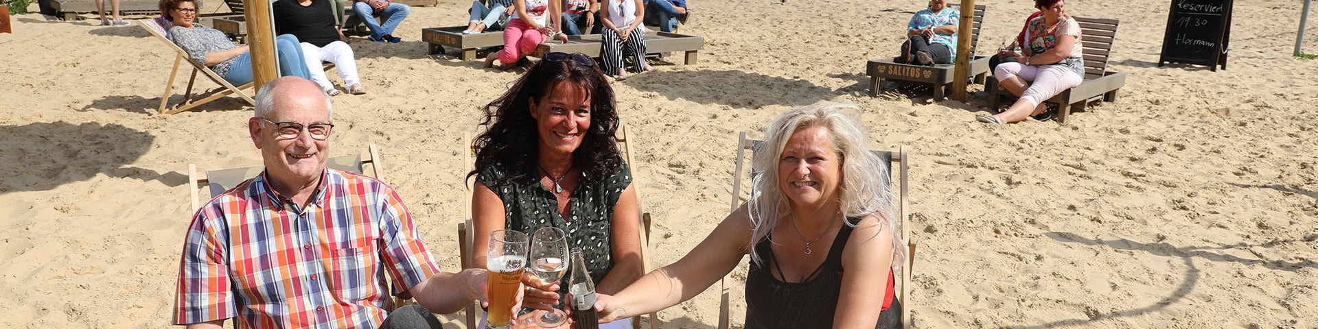 Gruppe sitzt Am Obersee Beach in Bielfeld und stößt mit Getränken an