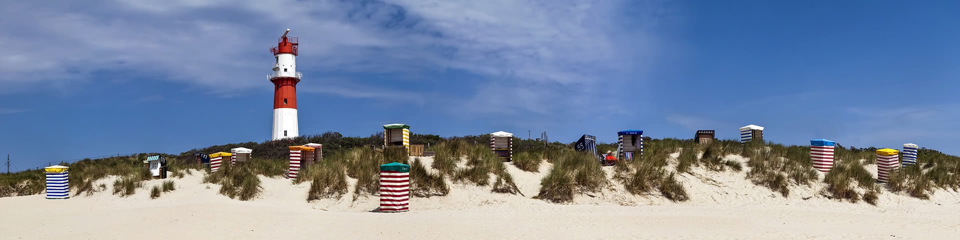 Strankörbe an eine kleinen Düne auf Borkum mit Leuchtturm