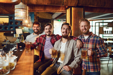 Vier Männer sitzen zusammen an einer Theke in einer Kneipe in Bremen und trinken Bier