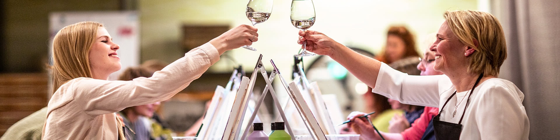 Zwei Frauen prosten sich mit einem Glas Wein zu bei einer Artnight in Bremen