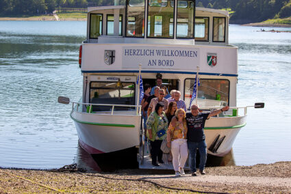 Gruppe verlässt gemeinsam ein Schiff am Ufer des Hennesee