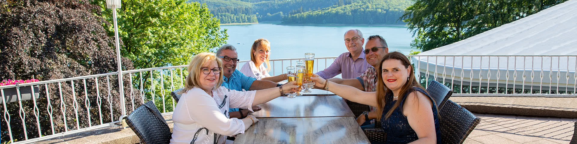 Gruppe trinkt gemeinsam Bier auf einer Terasse mit Blick auf den Hennesee