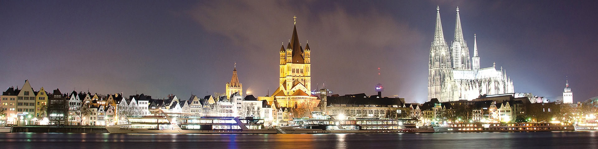 Schiffe auf dem Rhein vor der beleucteten Kölner Altstadt