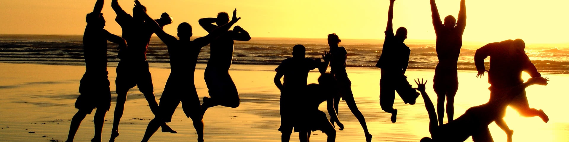 Gut gelaunte Gruppe am Strand bei Sonnenuntergang auf Mallorca