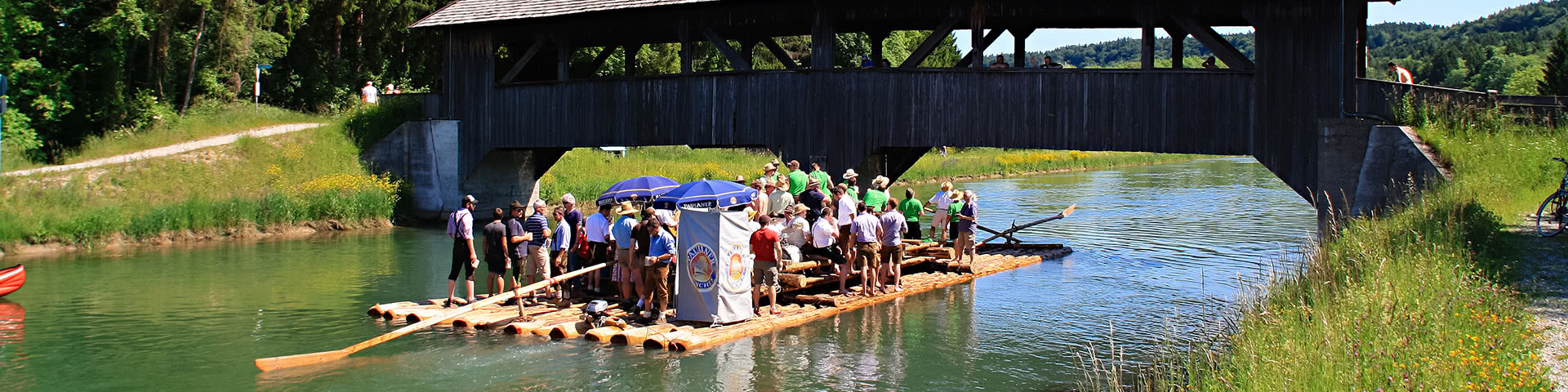 Floss fährt auf der Isar an einer Brücke vorbei in München