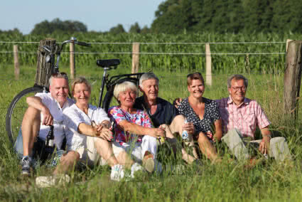 Drei Paare machen eine Pause von ihrer Radtour und sitzen auf einer Wiese