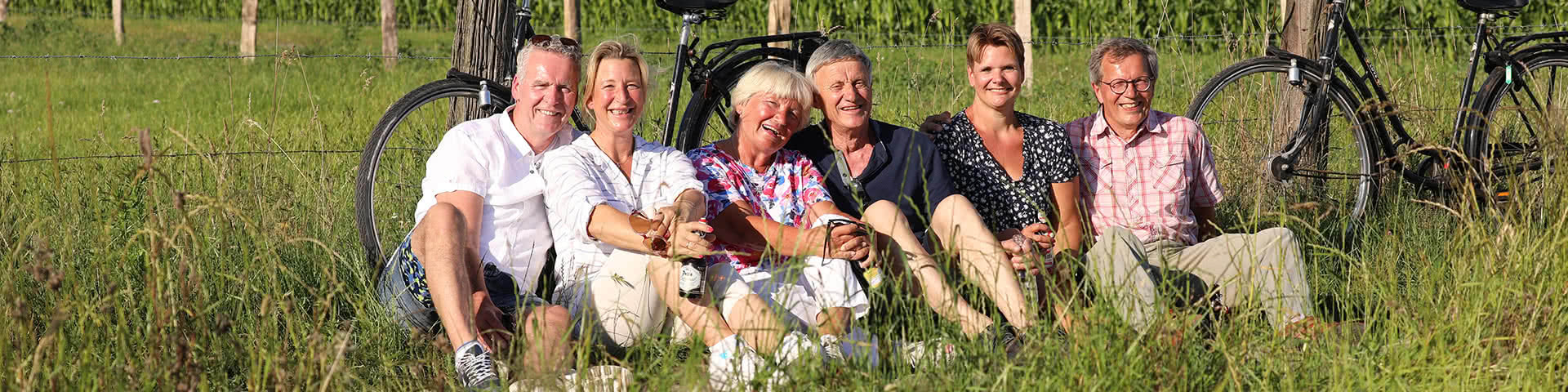 Drei Paare machen eine Pause von ihrer Radtour und sitzen auf einer Wiese