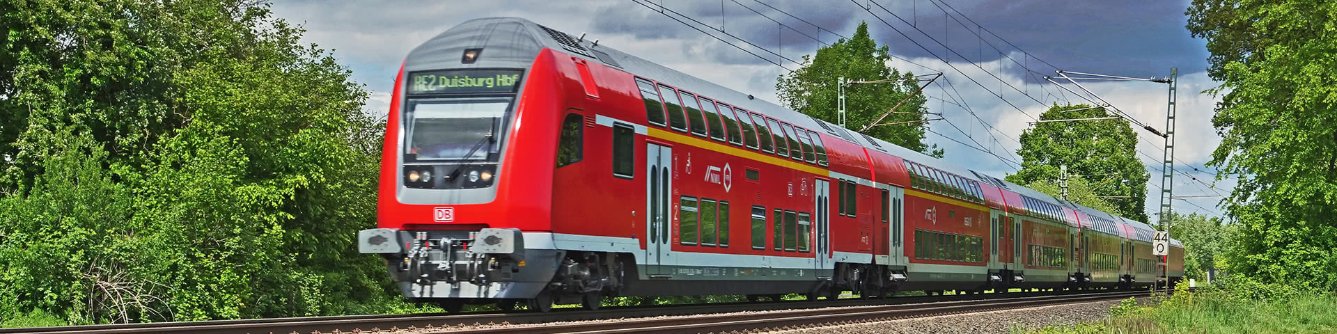 Zug der Deutschen Bahn auf Schienen mit Bäumen rechts und links