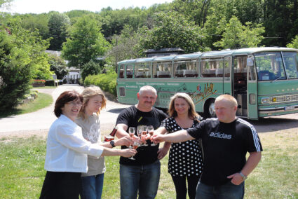 Gruppe steht vor dem Oldtimerbus und trinkt Sekt