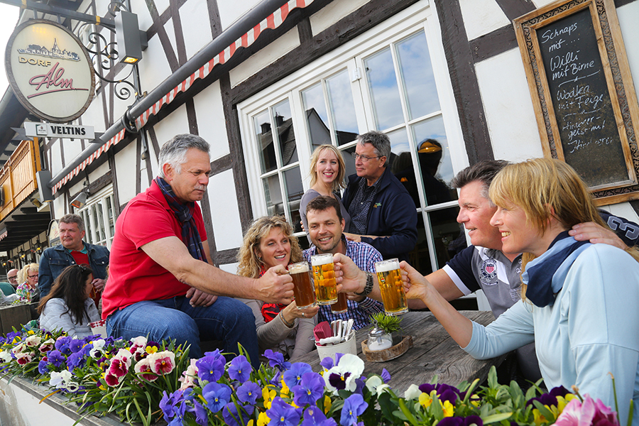 Gruppe trinkt gemeinsam Bier auf der Terasse vom Hotel Dorf Alm Willingen