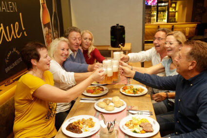 Gruppe isst gemeinsam zu Abend und stößt mit Bier an im Brauhaus in Willingen