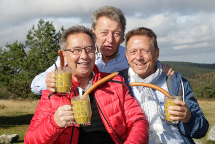 Männergruppe mit Erbesensuppe und Würstchen im Glas auf 